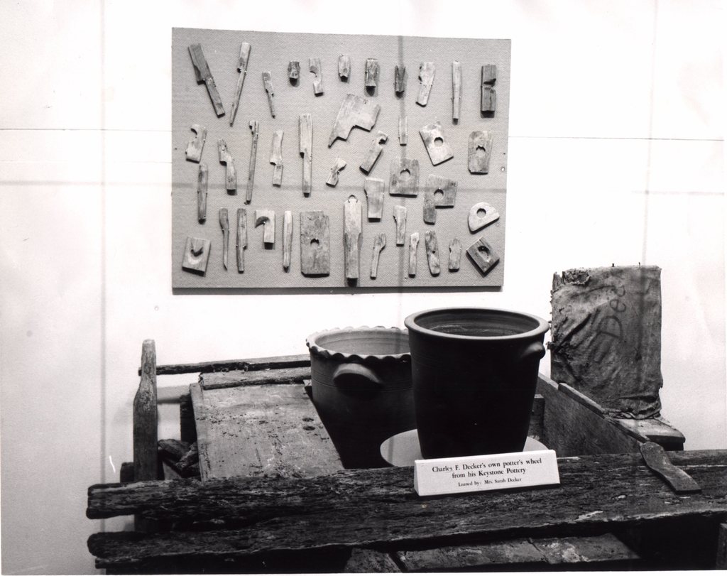 Photograph from an early exhibit showing Charles, Sr.â€™s wheel, tools and pottery. Burbage20.