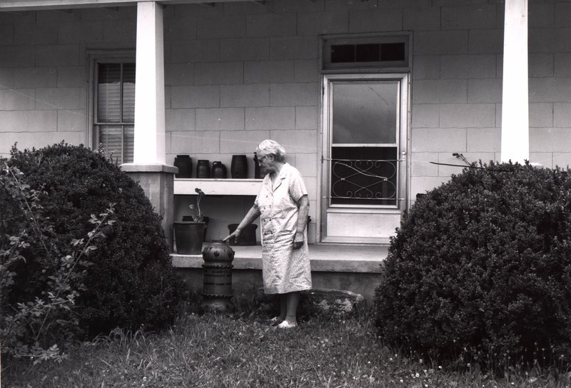 Mrs. Sarah Decker is seen standing in front of the old Decker home. The 1884 yard ornament is minus its top, which was reportedly broken by a grandson. Burbage12.